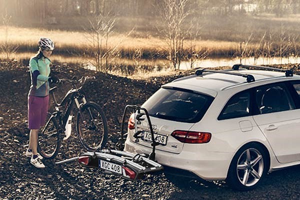 Cyclist rolling a bike onto a towbar car rack